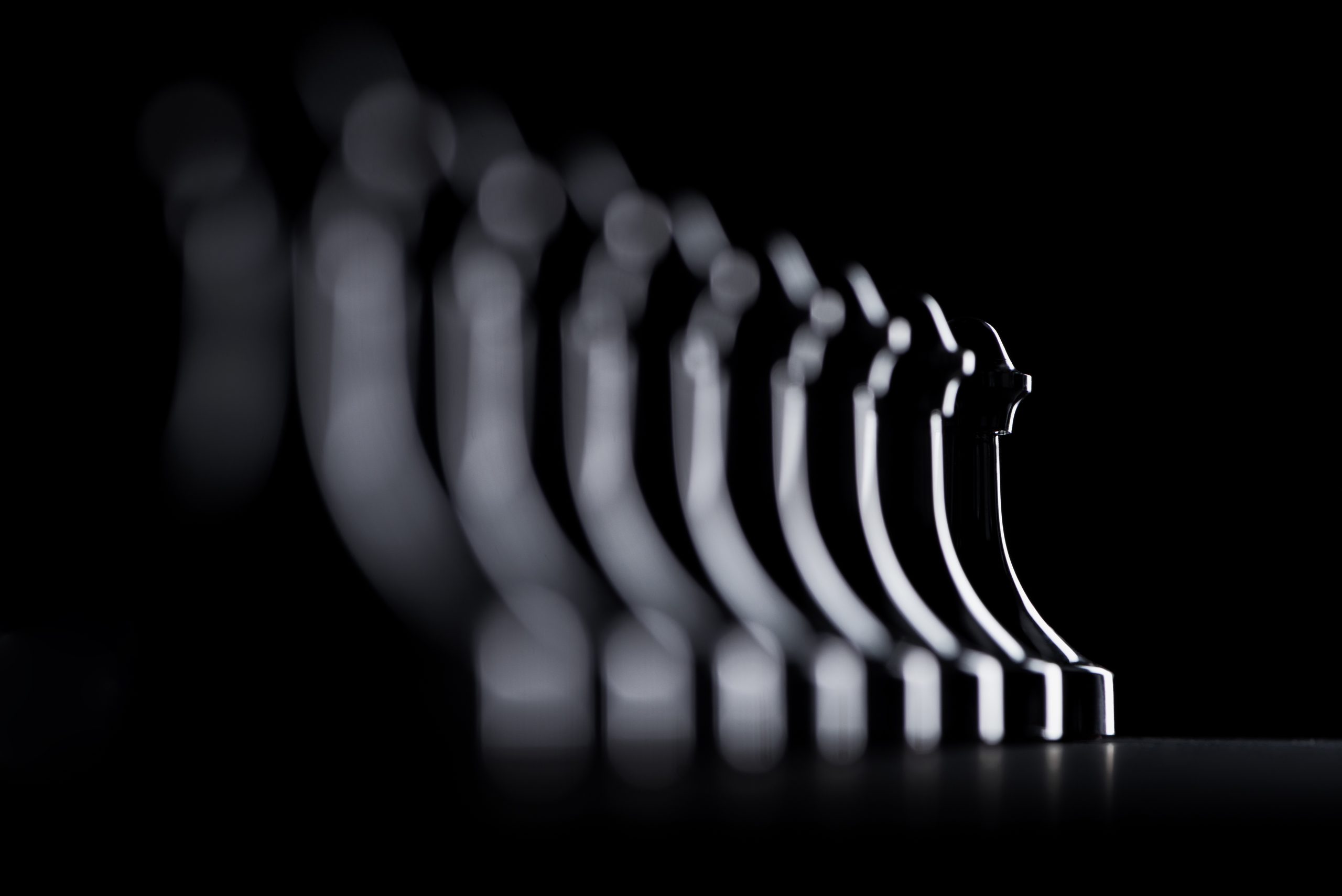 silhouettes of row of chess pawns isolated on black, business concept